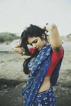 Malavika Mohanan in a blue floral sari and red blouse posing outdoors HD phone wallpaper