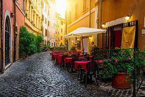 Charming Italian Street Cafe with Red Tablecloths and Cobblestone Path HD wallpaper