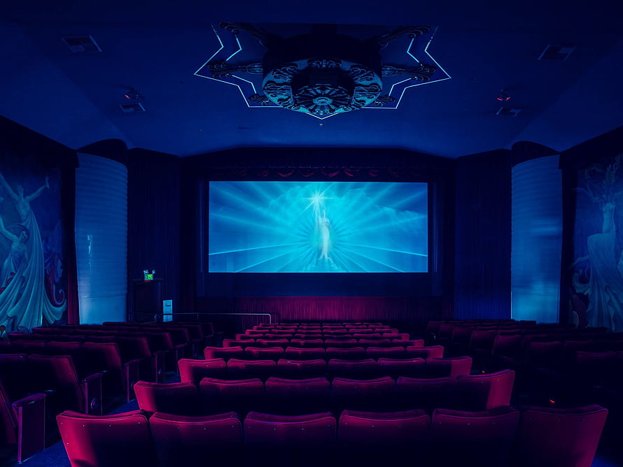 Cinematic Movie Theater Interior With Glowing Screen And Red Velvet Seating HD wallpaper