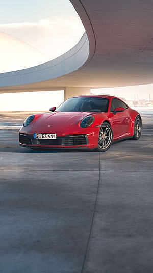 Red Porsche 911 Turbo S parked under a modern concrete overpass at dusk HD phone wallpaper