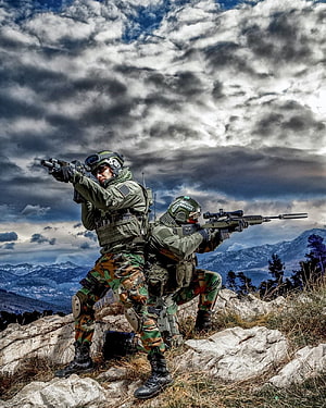Indian Army soldiers in tactical combat gear aiming rifles on a rocky mountain ridge under dramatic storm clouds HD phone wallpaper