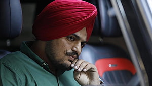 Sidhu Moose Wala in a red turban and green shirt with a contemplative expression HD wallpaper