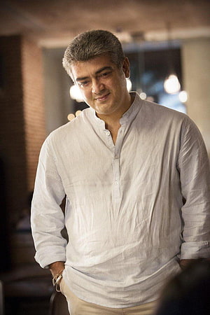 Ajith Kumar in a white linen shirt with a warm smile in a softly lit indoor setting HD phone wallpaper