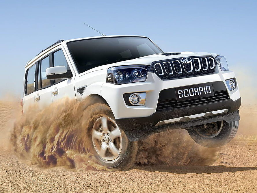 White Mahindra Scorpio SUV kicking up dust on a desert road under a clear blue sky HD wallpaper