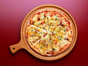 Cheesy Margherita Pizza on a Round Wooden Serving Board Against a Deep Red Background HD wallpaper
