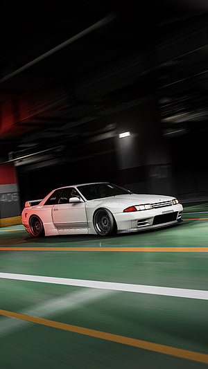 White Nissan Skyline R32 GT-R drifting through a dark underground parking garage with motion blur HD phone wallpaper