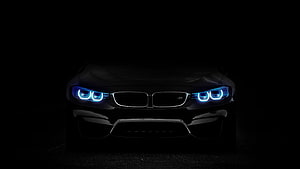 BMW M4 Front View With Glowing Blue Headlights In Dark Studio Setting HD wallpaper