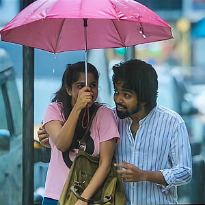 GV Prakash and female co-star sharing a pink umbrella in a rainy street scene from a Tamil film HD phone wallpaper