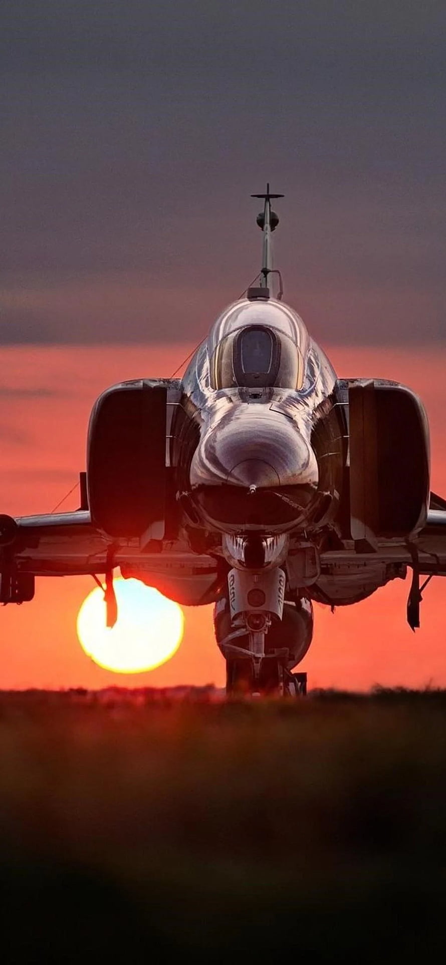 F-4 Phantom II fighter jet front view silhouetted against a dramatic sunset sky HD phone wallpaper