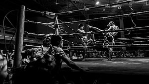 Black and White Muay Thai Fighters Exchanging High Kicks in a Traditional Boxing Ring HD wallpaper