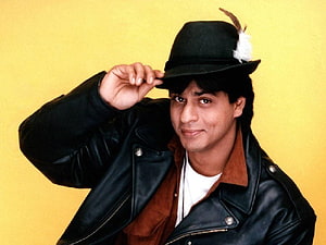Shah Rukh Khan in a black leather jacket and feathered hat against a yellow background HD wallpaper