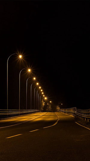 Empty Highway at Night Illuminated by a Row of Warm Street Lamps HD phone wallpaper