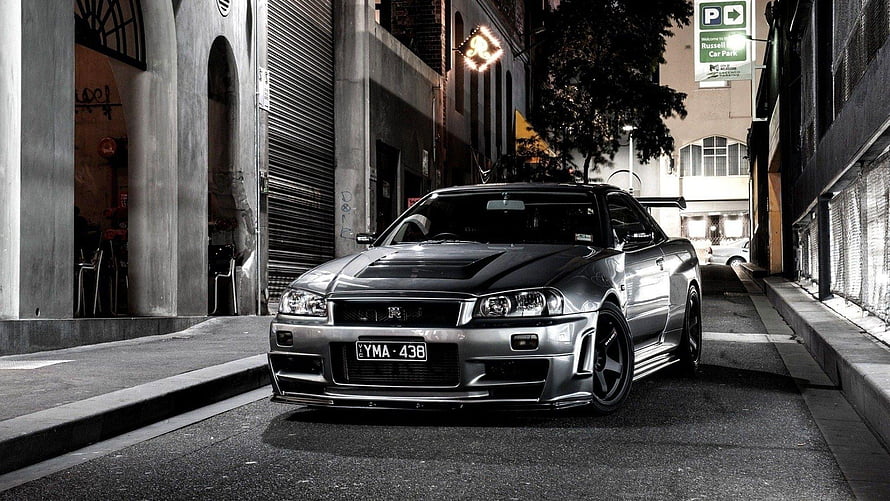 Nissan Skyline GT-R R34 parked on a dimly lit urban street at night HD wallpaper