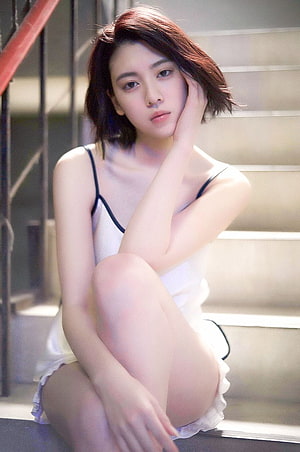 Ayaka Miyoshi in a white slip dress sitting on concrete stairs with soft natural lighting HD phone wallpaper