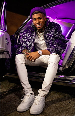 Nle Choppa in purple bandana jacket and white outfit sitting on a car step with neon lighting HD phone wallpaper