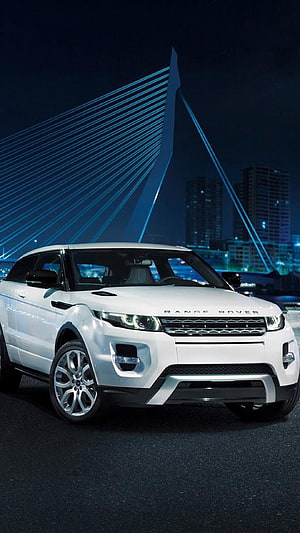 White Range Rover Evoque parked at night with illuminated cable-stayed bridge and city skyline in the background HD phone wallpaper