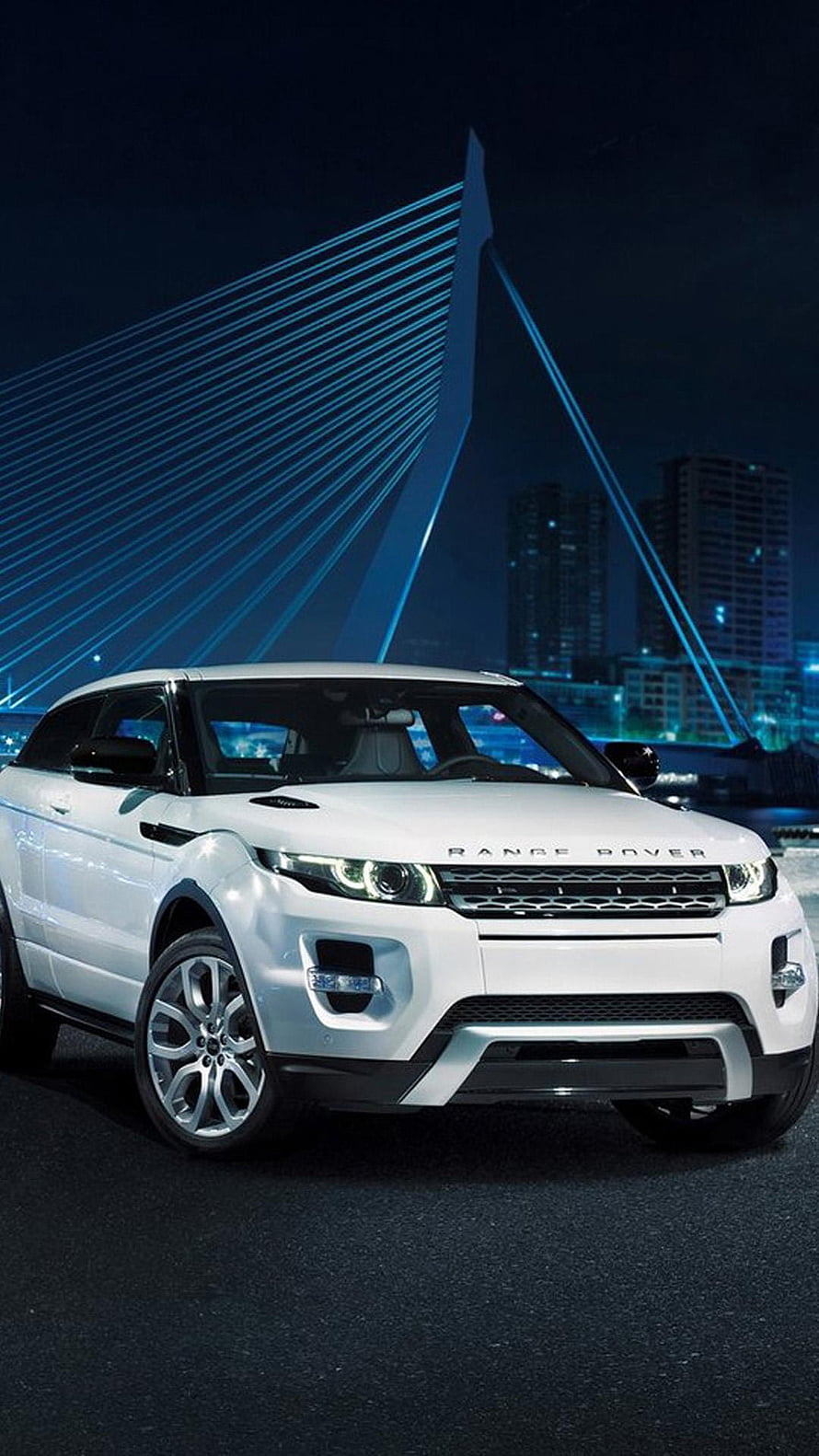 White Range Rover Evoque parked at night with illuminated cable-stayed bridge and city skyline in the background HD phone wallpaper