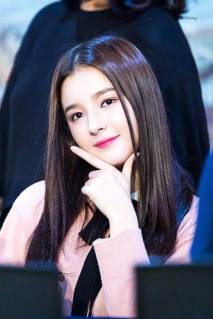 Momoland Nancy in a soft pink sweater with a gentle smile and finger on chin HD phone wallpaper