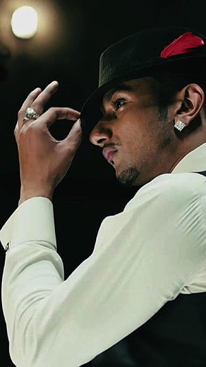 Honey Singh in a white suit and black fedora with a red feather, adjusting his hat against a dark background HD phone wallpaper