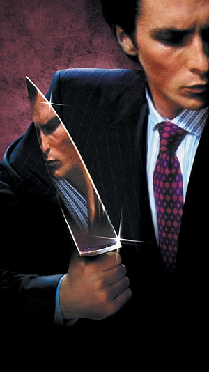 Patrick Bateman from American Psycho holding a knife in a dark suit HD phone wallpaper