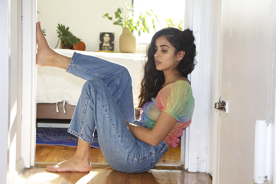 Parveen Kaur in Rainbow Top and Denim Jeans Sitting in Sunlit Doorway HD wallpaper