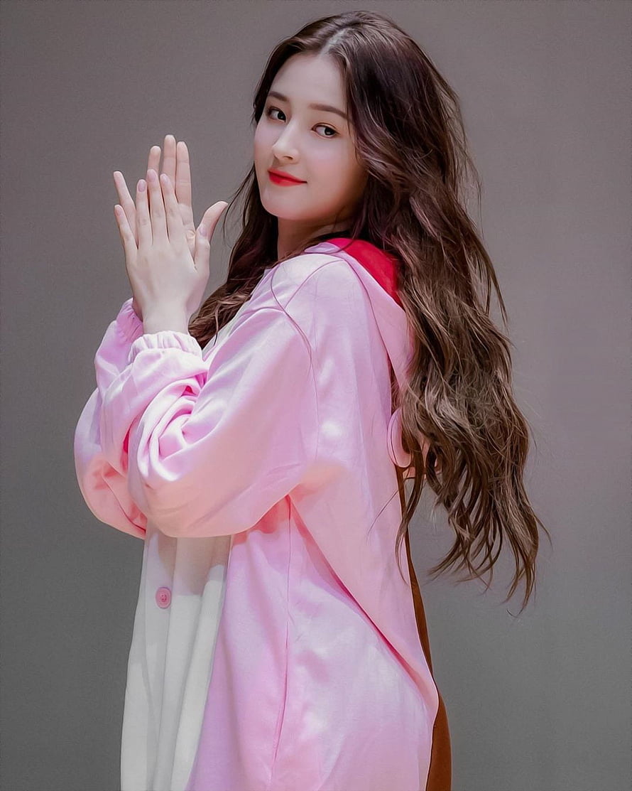 Nancy from Momoland in a soft pink satin jacket with long wavy hair and a gentle smile HD phone wallpaper