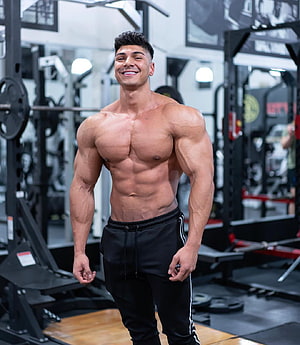 Andrei Deiu posing shirtless in a modern gym showcasing defined muscle definition and athletic physique HD phone wallpaper