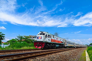 KAI Loco 2500 Diesel Locomotive Pulling Passenger Train on Rural Tracks Under Blue Sky HD wallpaper