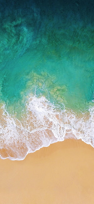Aerial View of Turquoise Ocean Waves Lapping Against Golden Sand Beach HD phone wallpaper