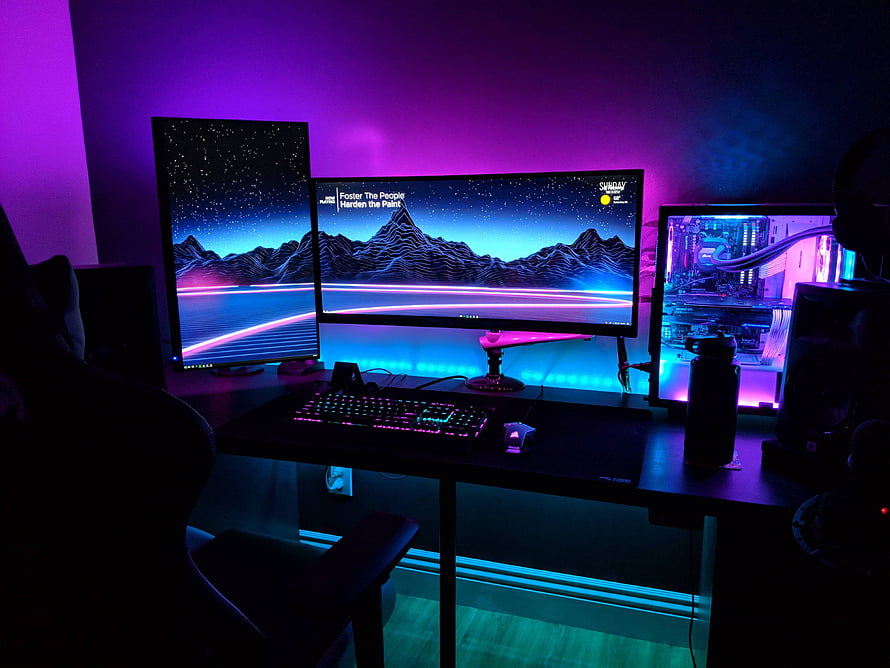 Neon-lit gaming battlestation with ultrawide and portrait monitors HD wallpaper