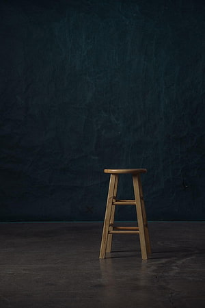 Minimalist wooden stool against a dark textured studio backdrop HD phone wallpaper