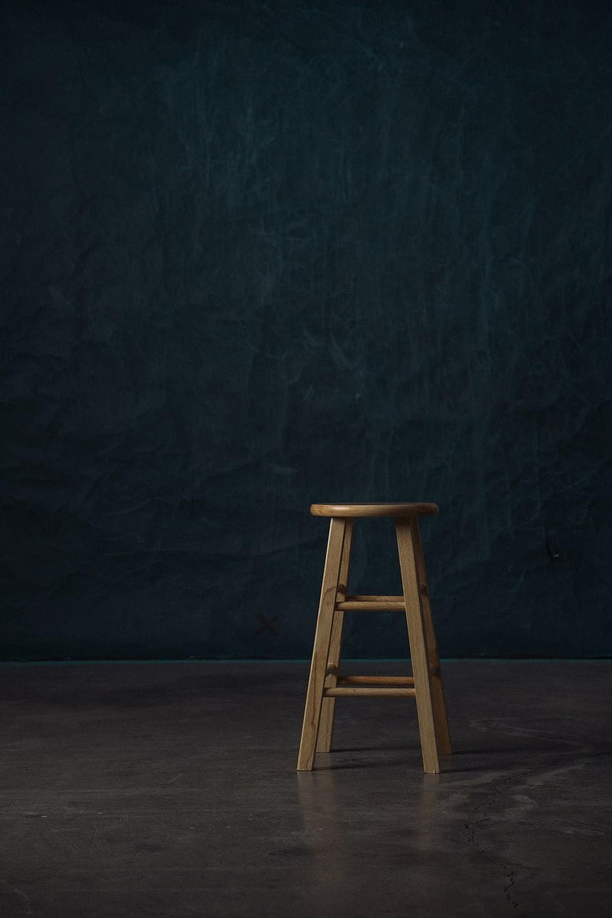 Minimalist wooden stool against a dark textured studio backdrop HD phone wallpaper