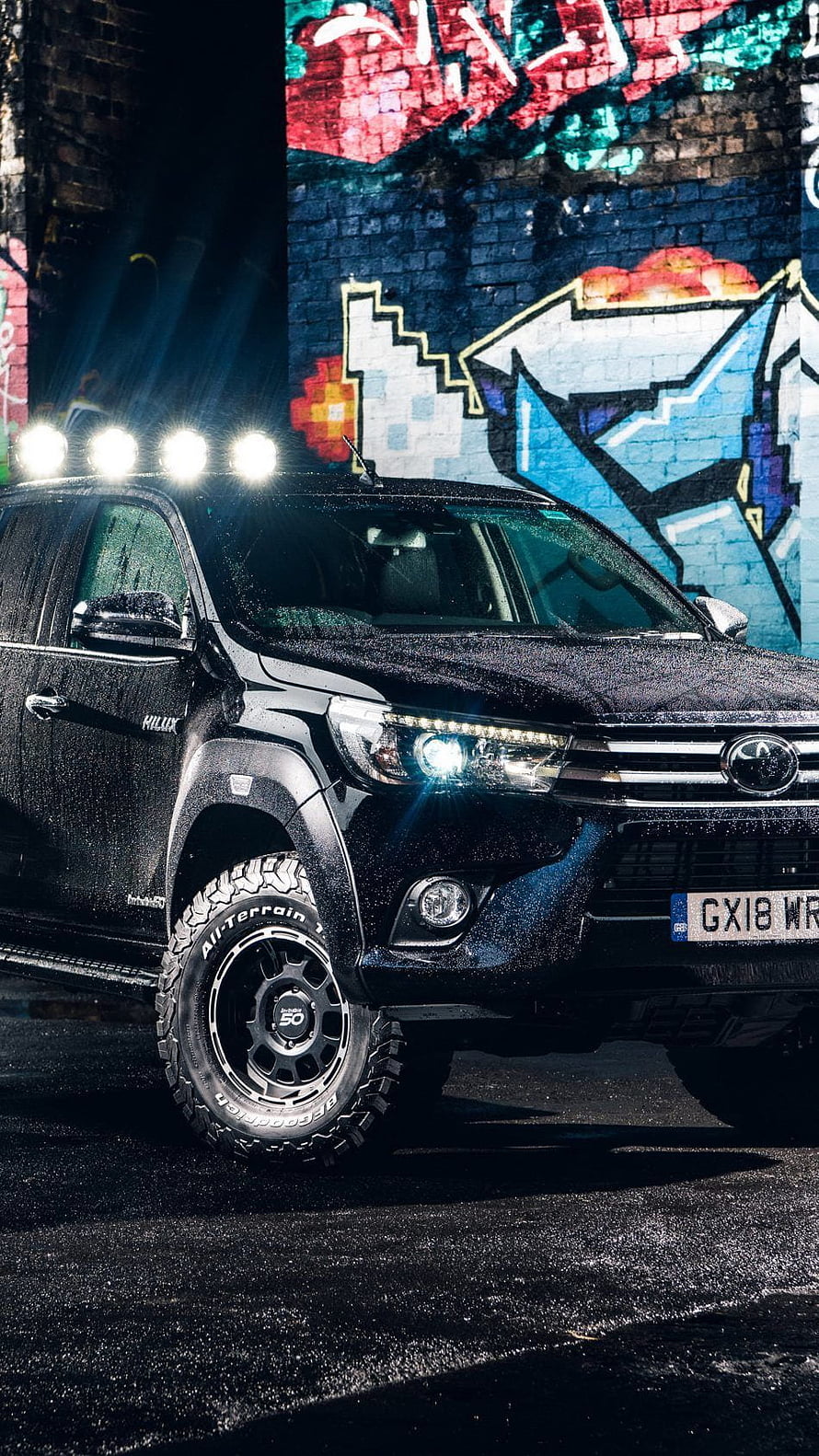 Black Toyota Hilux Pickup Truck with Off-Road Tires Parked Against Vibrant Street Art Mural HD phone wallpaper