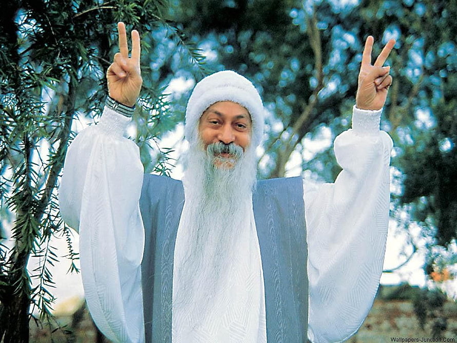 Osho Rajneesh in white robes making peace signs outdoors HD wallpaper