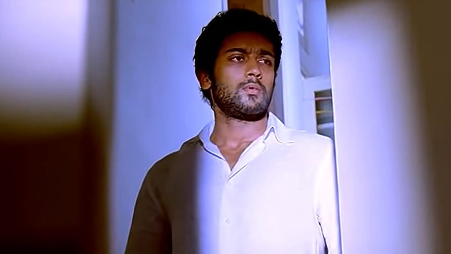 Surya in a white shirt with a serious expression in a dimly lit interior HD wallpaper