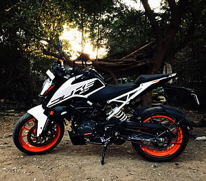 KTM Duke 200 motorcycle with orange wheels parked in a forest clearing at sunset HD wallpaper