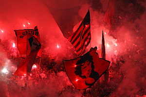 Flamengo Fans Waving Flags in Red Smoke at a Nighttime Stadium HD wallpaper