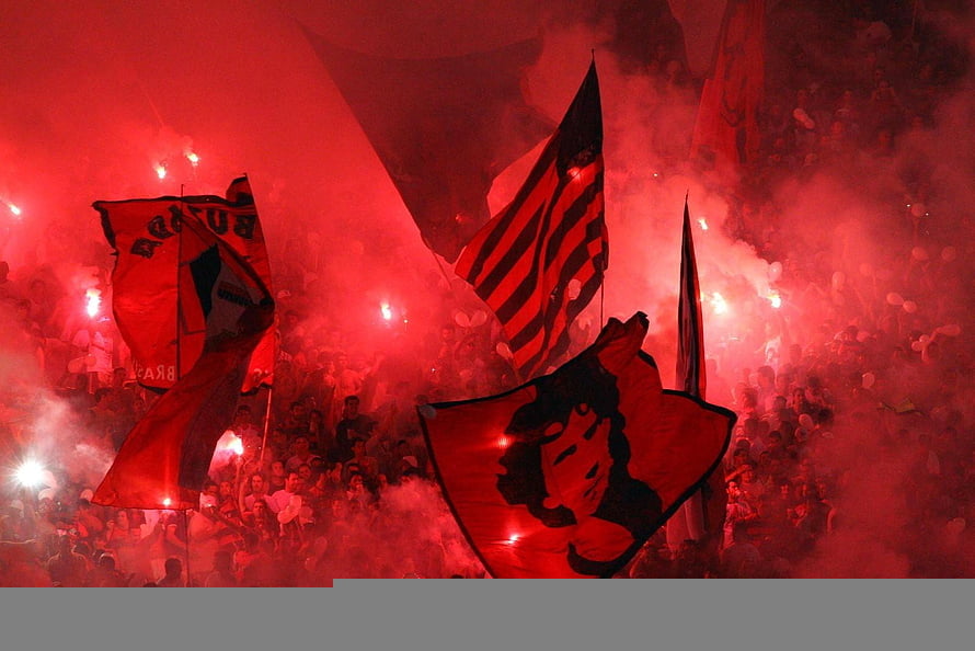 Flamengo Fans Waving Flags in Red Smoke at a Nighttime Stadium HD wallpaper