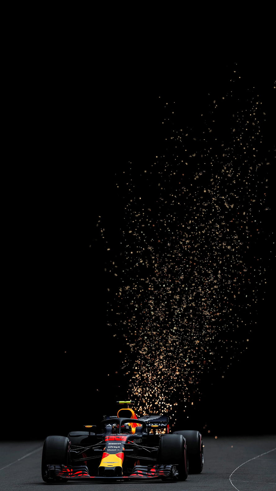 Red Bull Racing Formula 1 car launching sparks on a dark race track at night HD phone wallpaper
