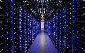 Vast Data Center Aisle with Glowing Blue Server Racks and Network Infrastructure HD wallpaper
