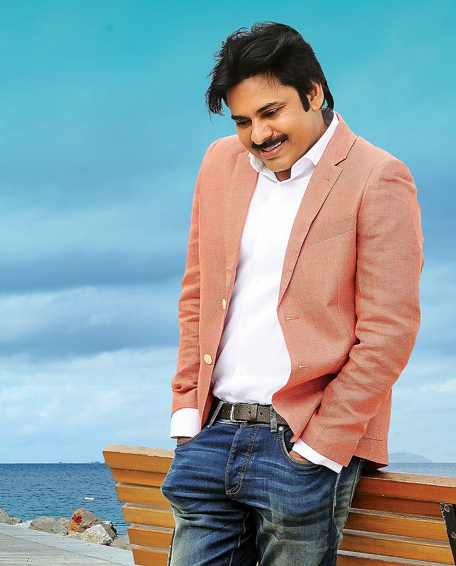 Pawan Kalyan in a peach blazer and jeans leaning on a seaside bench HD phone wallpaper
