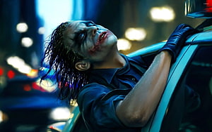 The Joker Leaning Against a Police Car in a Rainy Night Scene HD wallpaper