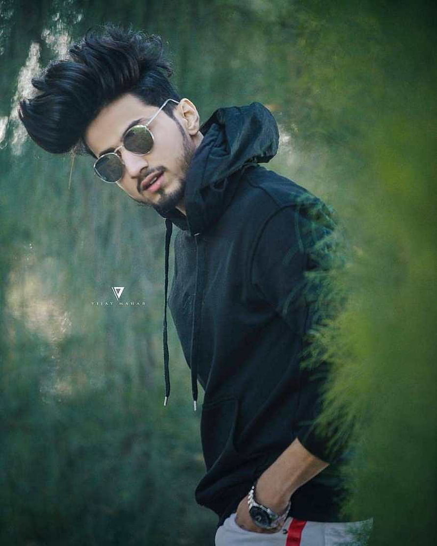 Stylish Young Man in Black Hoodie and Round Sunglasses in a Lush Green Forest HD phone wallpaper