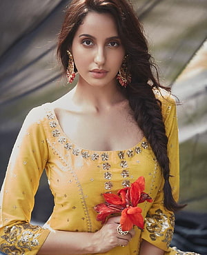 Nora Fatehi in a yellow embroidered kurta holding red flowers with a long braid HD phone wallpaper