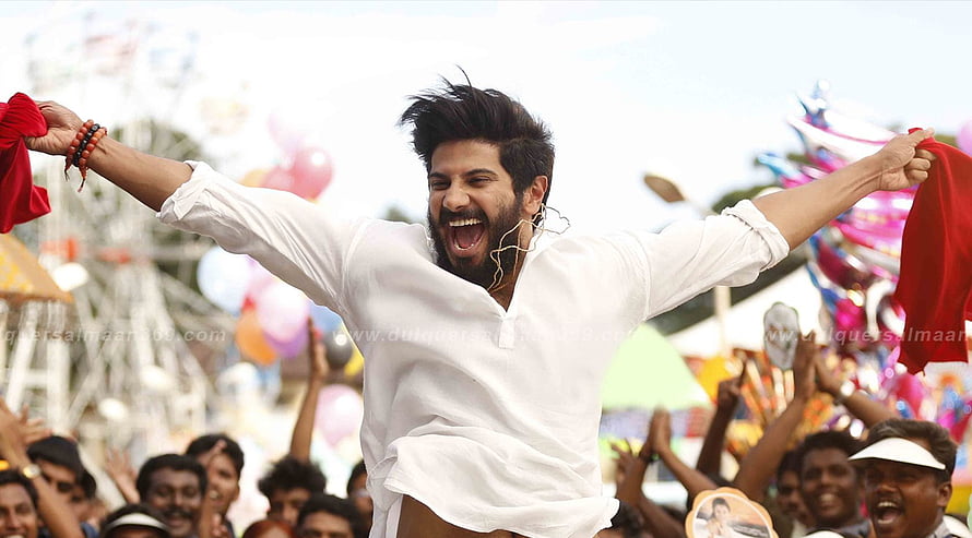 Dulquer Salmaan as Charlie in the Malayalam film Charlie, celebrating with arms raised before a cheering crowd HD wallpaper