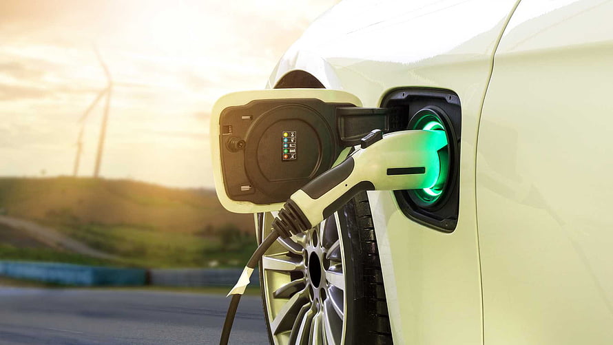 White Electric Vehicle Charging With Green Indicator Light And Wind Turbines In Background HD wallpaper