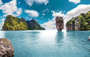 Tropical limestone karst islands rising from turquoise ocean waters under a bright blue sky HD wallpaper