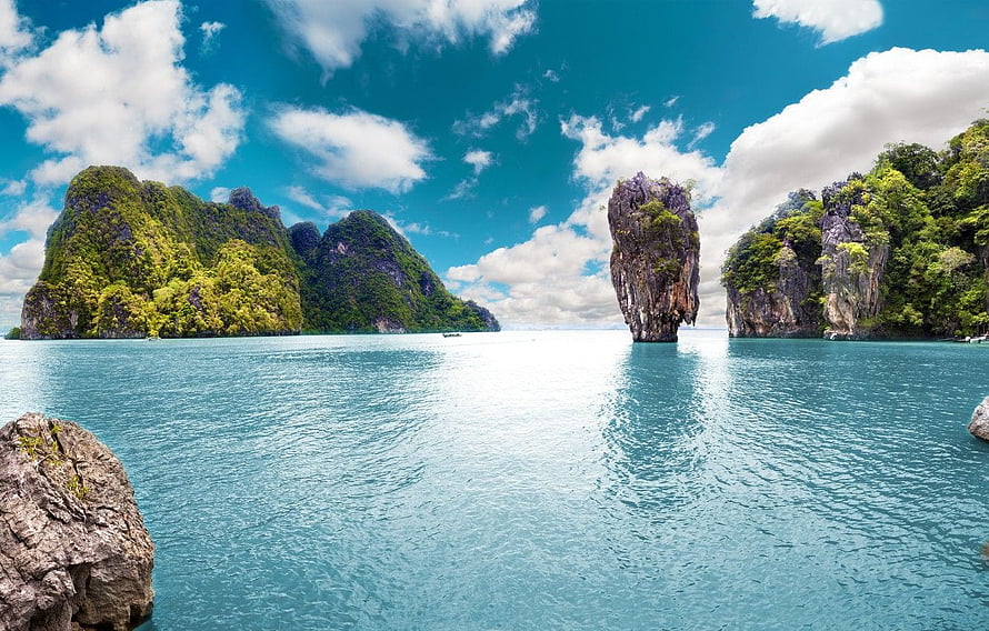 Tropical limestone karst islands rising from turquoise ocean waters under a bright blue sky HD wallpaper