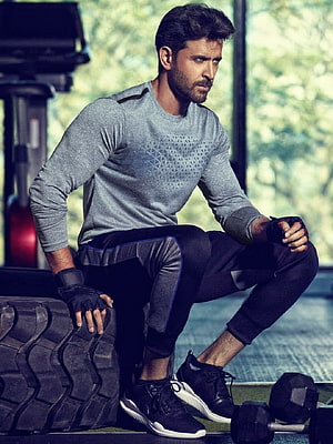 Hrithik Roshan in athletic wear seated on gym tire with dumbbells HD phone wallpaper