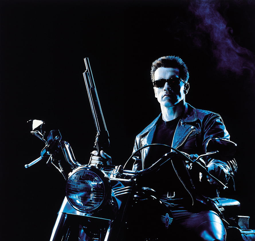 Arnold Schwarzenegger as the Terminator on a motorcycle with a shotgun in a dark cinematic scene HD wallpaper